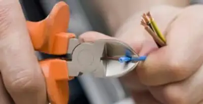licensed electrician performing precise wire cutting and preparation during electrical service in Seattle, WA