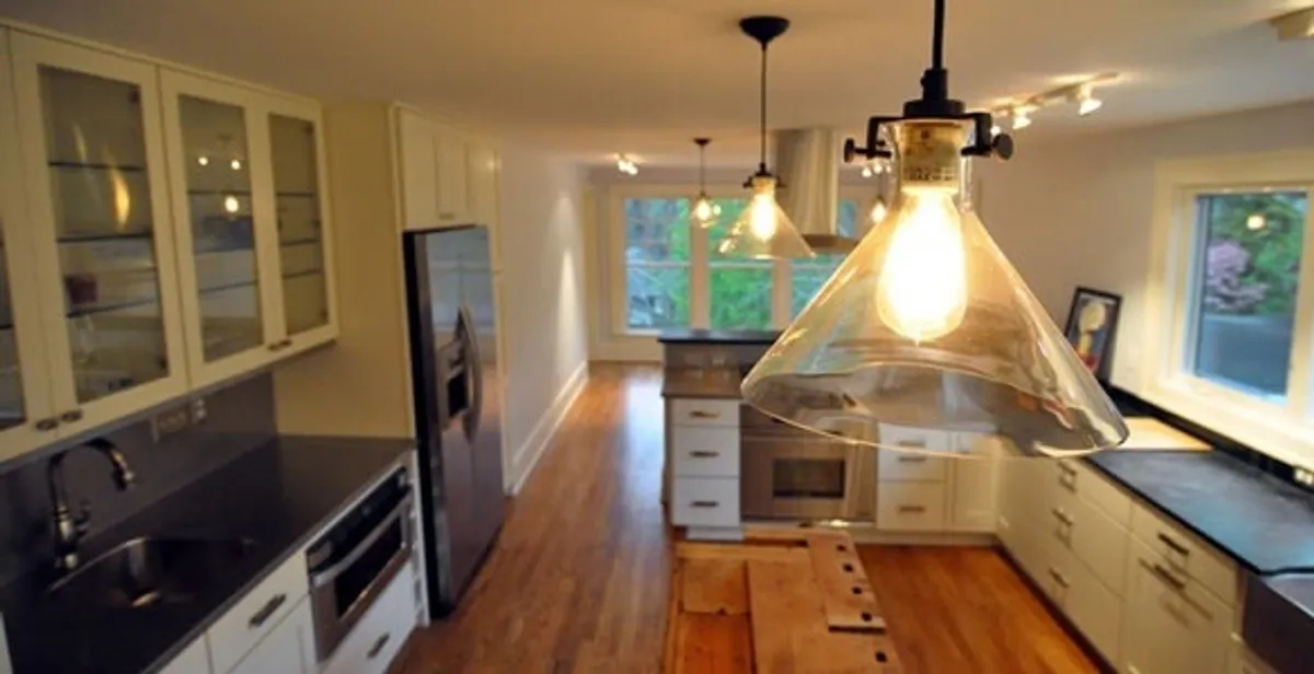 Residential electrician installing modern indoor light fixture in a home in Seattle, WA