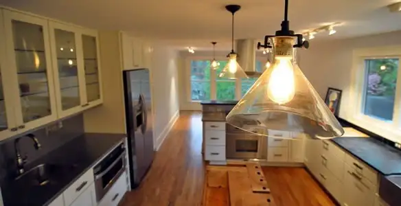 Residential electrician installing modern indoor light fixture in a home in Seattle, WA