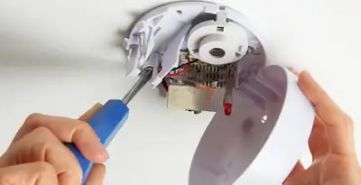 Certified technician wiring smoke detector during installation in Seattle, WA